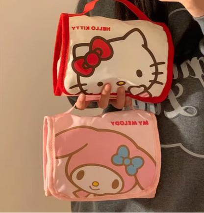 Two Hello Kitty bags, one beige with a red bow and one pink with a blue bow, held by a person.